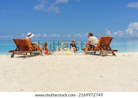 family building a sandcastle at the beach in summer - vacation time Royalty-Free Stock Photo #2169972749