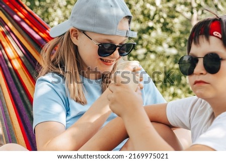 Happy Boy girls eating vanilla ice cream outdoors in home garden backyard at vacation. Candid Smiling Teen child licking icecream refreshing in heat. Summer cooling off.