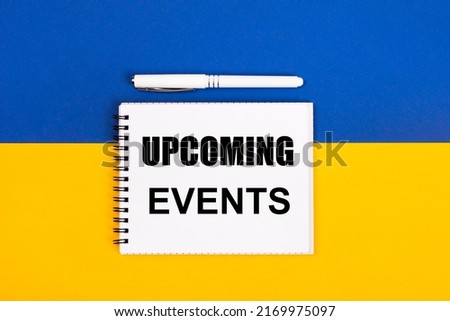 A white notebook with the text UPCOMING EVENTS and a white pen on a blue and yellow background.