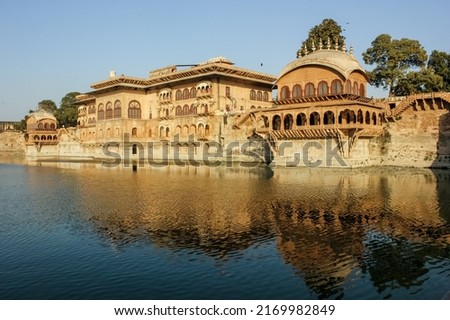 The exterior facade of the ancient royal palace rising above the waters of a lake in the town of Deeg in Rajasthan, India. Royalty-Free Stock Photo #2169982849