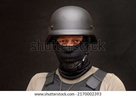 muscular military 45-50 years old in a bulletproof vest and balaclava, army helmet on his head, black background. Concept: volunteer at war, war in Ukraine, civil self-defense, army unit.