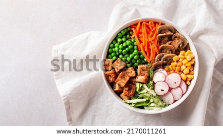 Vegan buddha bowl with tofu, colorful vegetables on base of brown rice. Top view, healthy vegetarian bowl dish on white table, top view, copy space