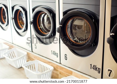 Public laundry. Row of industrial laundry machines in laundromat. Royalty-Free Stock Photo #2170011877