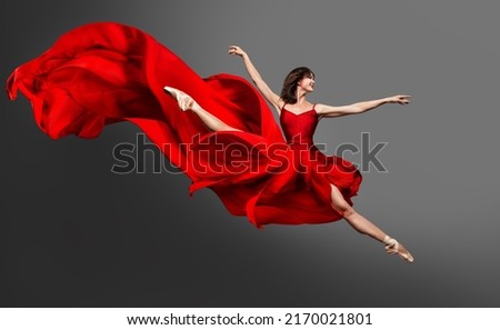 Ballerina Dance. Ballet Dancer in Red Dress jumping Split. Woman in Ballerina Shoes dancing in Silk Gown flying on Wind over Gray Studio Background