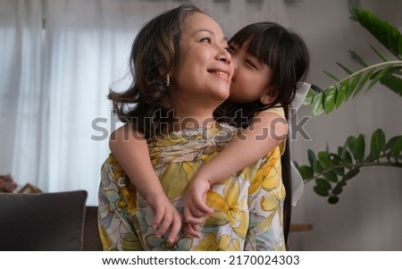 Cute little girl embracing and kissing her grandmother. Love and relation of difference generation in family lifestyle concept.