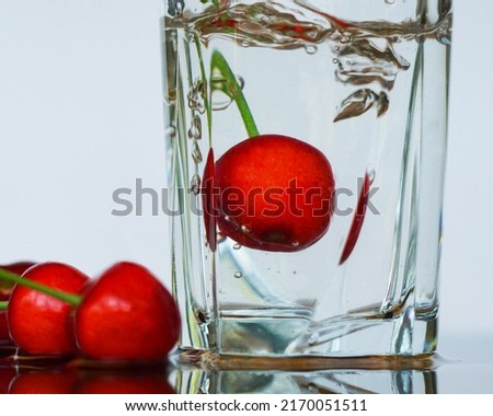                          Red cherries in a glass of water, red cherries are immersed in water     