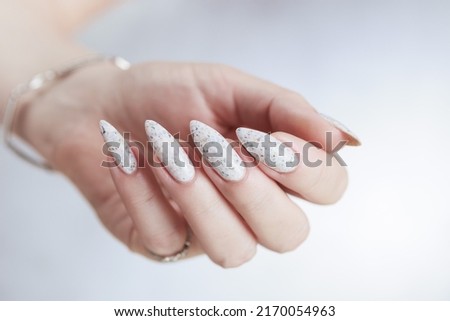 beautiful female hands with long nails light white manicure and a bottle of nail polish Royalty-Free Stock Photo #2170054963