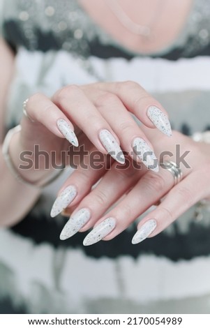 beautiful female hands with long nails light white manicure and a bottle of nail polish