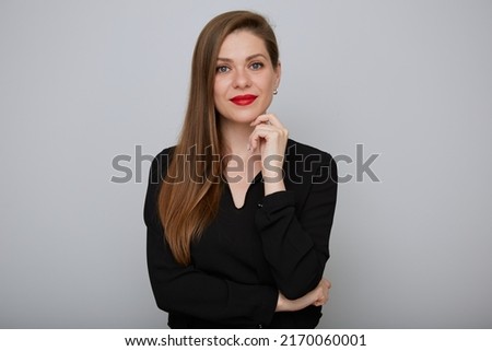 Smiling young business woman in black shirt touching her chin, isolated female portrait.