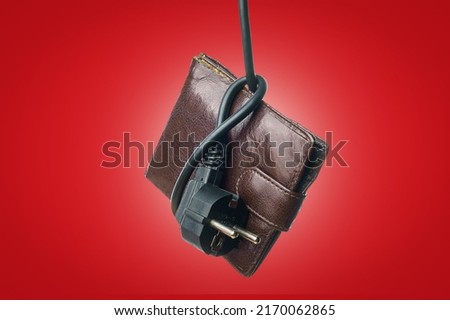 An electric cord with a plug tied in a knot on an old wallet. The concept of the energy crisis and electricity inflation. Rise in electricity prices. Copy space for text. Vignetting effect.