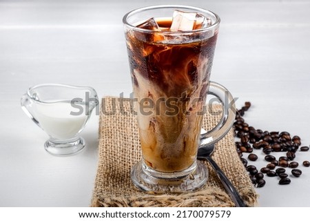 Cold coffee in a glass with ice and cream