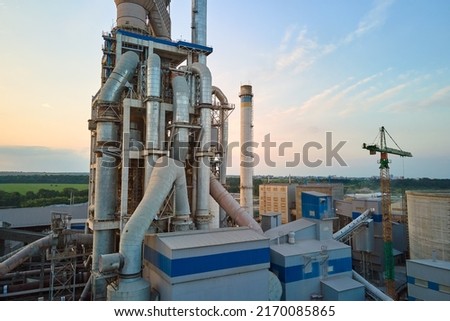 Aerial view of cement factory with high concrete plant structure and tower crane at industrial production site. Manufacture and global industry concept