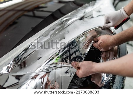 Car wrapping specialists putting silver mirror chrome foil on car. Selective focus. 