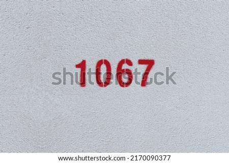 Red Number 1067 on the white wall. Spray paint.

