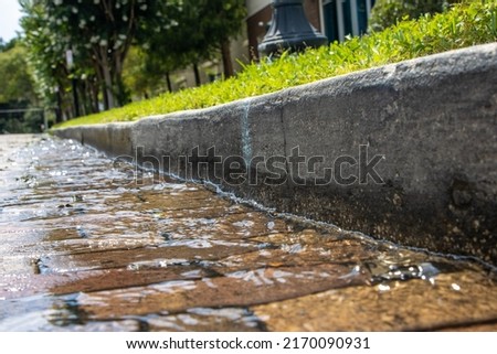 Water running over bricks after heavy rain storm in a city. Storm runoff. Royalty-Free Stock Photo #2170090931