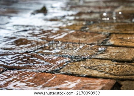 Water running over bricks after heavy rain storm in a city. Storm runoff. Royalty-Free Stock Photo #2170090939