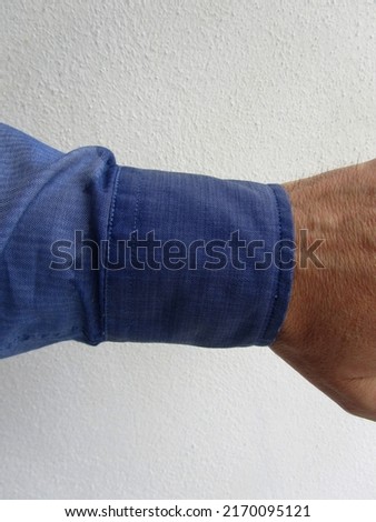 Cropped photo of wrist with wet shirt cuff from rain