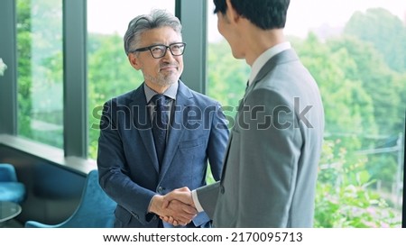 Middle aged executive man and young businessperson shaking hands in the office. Royalty-Free Stock Photo #2170095713