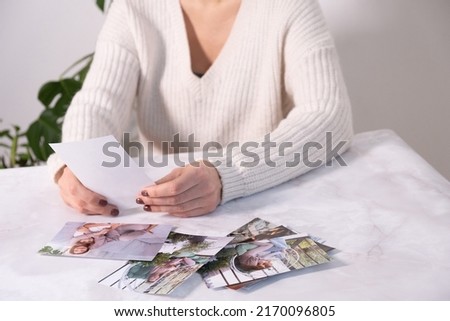 woman sitting at desk and looking at printed photos, remember nostalgia for a day of rest. photography cards, background. Mock up