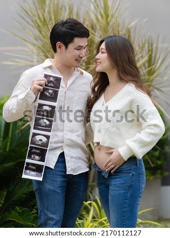 happy pregnant woman with her husband holding ultrasound photo of baby. married couple.