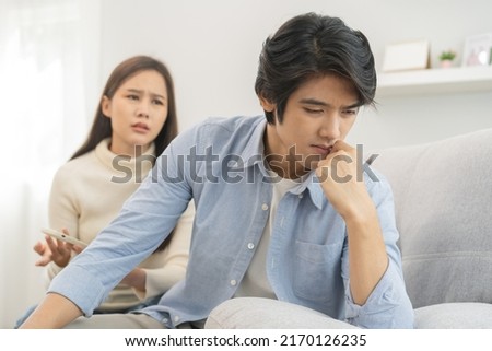 Infidelity, suspicion asian young couple love fight relationship, wife holding cellphone, smartphone cheating on phone, scolding husband about mistrust, distrust and jealousy when sitting at home. Royalty-Free Stock Photo #2170126235