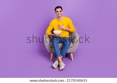 Photo of cheerful excited smiling man sit cozy armchair watching good comedy film isolated on purple color background