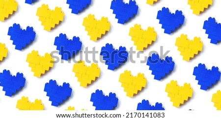 Hearts from  toy blocks as background, minimal geometric pattern from plastic blocks blue and yellow color, shapes heart from child construction. Top view repeat pattern, Toys and games