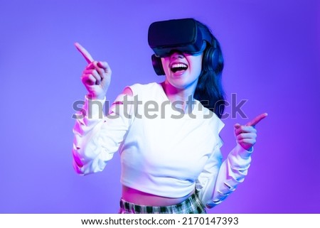 Metaverse concept, young asian girl in white fashion sweatshirt wearing vr headset playing touching online game purple background.