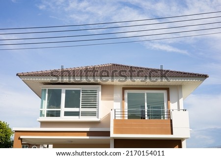 The roof of the house has electrical wires running across the blue sky background.