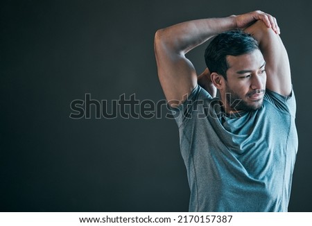Getting in a good pre-workout warmup. Cropped shot of a handsome young male athlete warming up against a grey background. Royalty-Free Stock Photo #2170157387