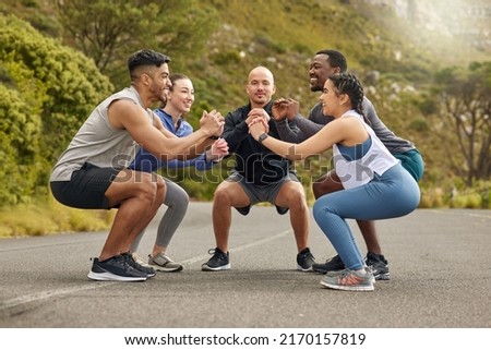 We can only go far if we warmup well. Shot of a group of sporty young people doing squats while exercising together outdoors. Royalty-Free Stock Photo #2170157819