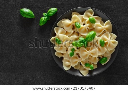 Farfalle, cooked pasta with basil green leaves, on dark background, top view, space to copy text.
 Royalty-Free Stock Photo #2170175407