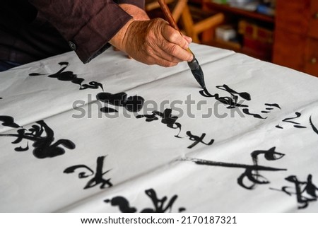 An old calligrapher is writing and creating calligraphy works. Translation: It rains on the pond with light thunder outside Liuwai, and the sound of rain drops and smashes the lotus.