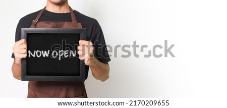 Cropped portrait of Asian barista man holding a blackboard holding a blackboard that says "Now Open" good for banner. Isolated image on white background.