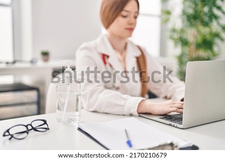 Young blonde woman wearing doctor uniform using sanitizer gel hands at clinic