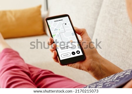 Woman on the sofa checking an online order status with delivery tracking app on smartphone.  Royalty-Free Stock Photo #2170215073
