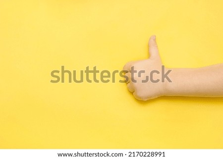 child's hand shows a like on a blue background with a copy space.
