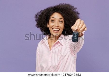 Young smiling fun cool happy cheerful woman of African American ethnicity 20s wear pink striped shirt hold give car keys keyless system isolated on plain pastel light purple background studio portrait