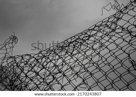 Wire fence or metal net on sunset background, blue sky. hole in net .