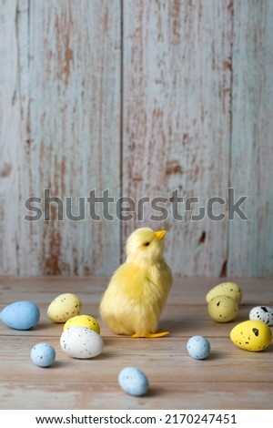 Easter greeting card with small chicken surrounded with colorful eggs against blue background.Vertical banner