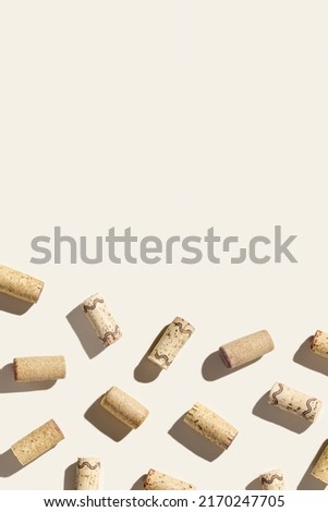 Creative pattern with wine corks on beige background with hard light and shadows at sunlight. Minimal style layout with bottle stoppers from red white wine, top view, wine list backdrop, copy space