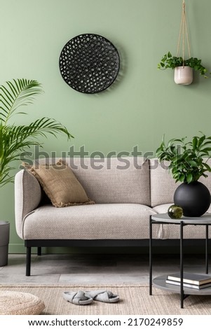 The stylish composition at living room interior with green wall, design gray sofa, coffee table, dark ornament and elegant personal accessories. Beige pillow. Cozy apartment. Template. 
 Royalty-Free Stock Photo #2170249859