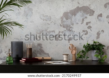 Concrete interior of home office with copy space. Black desk, image, lamp and office accessories. Grey concrete wall. Home decor. Template.  Royalty-Free Stock Photo #2170249937