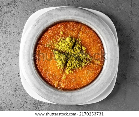 Turkish dessert kunefe, kunafa, kadayif with pistachio powder and cheese, served hot, very sweet. Turkish traditional dessert on grey background, top view Royalty-Free Stock Photo #2170253731