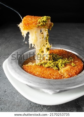 Turkish dessert kunefe, kunafa, kadayif with pistachio powder and cheese, served hot, very sweet. Turkish traditional dessert on grey background Royalty-Free Stock Photo #2170253735