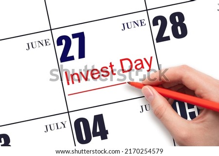 27th day of June. Hand drawing red line and writing the text Invest Day on calendar date June 27.  Business and financial concept. Summer month, day of the year concept.