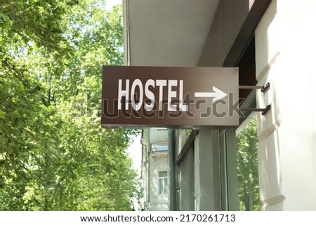 HOSTEL lightbox signage with arrow on building wall outdoors