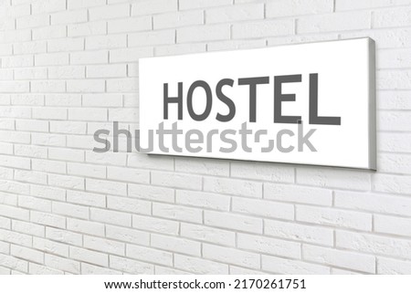 HOSTEL sign board on white brick wall