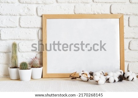 Square wooden photo frame and cactus plants on the table, close up