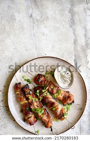Roasted chicken kebab or souvlaki on a plate over light grey slate, stone or concrete background. Top view with copy space.